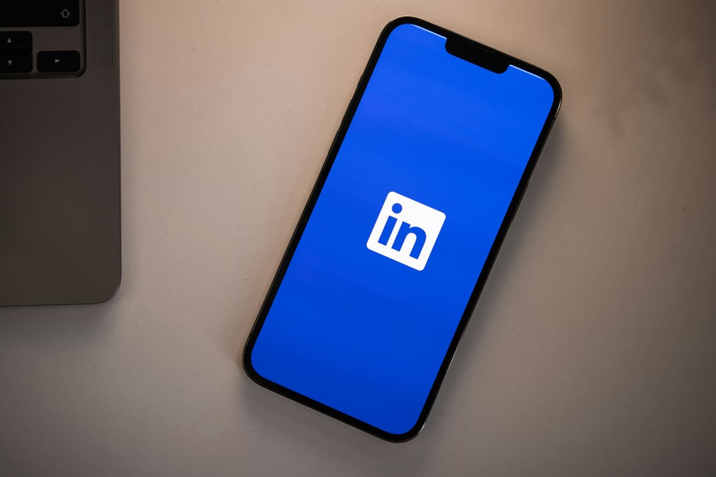 Phone showing the LinkedIn logo next to a laptop — B2B LinkedIn advertising and pipeline